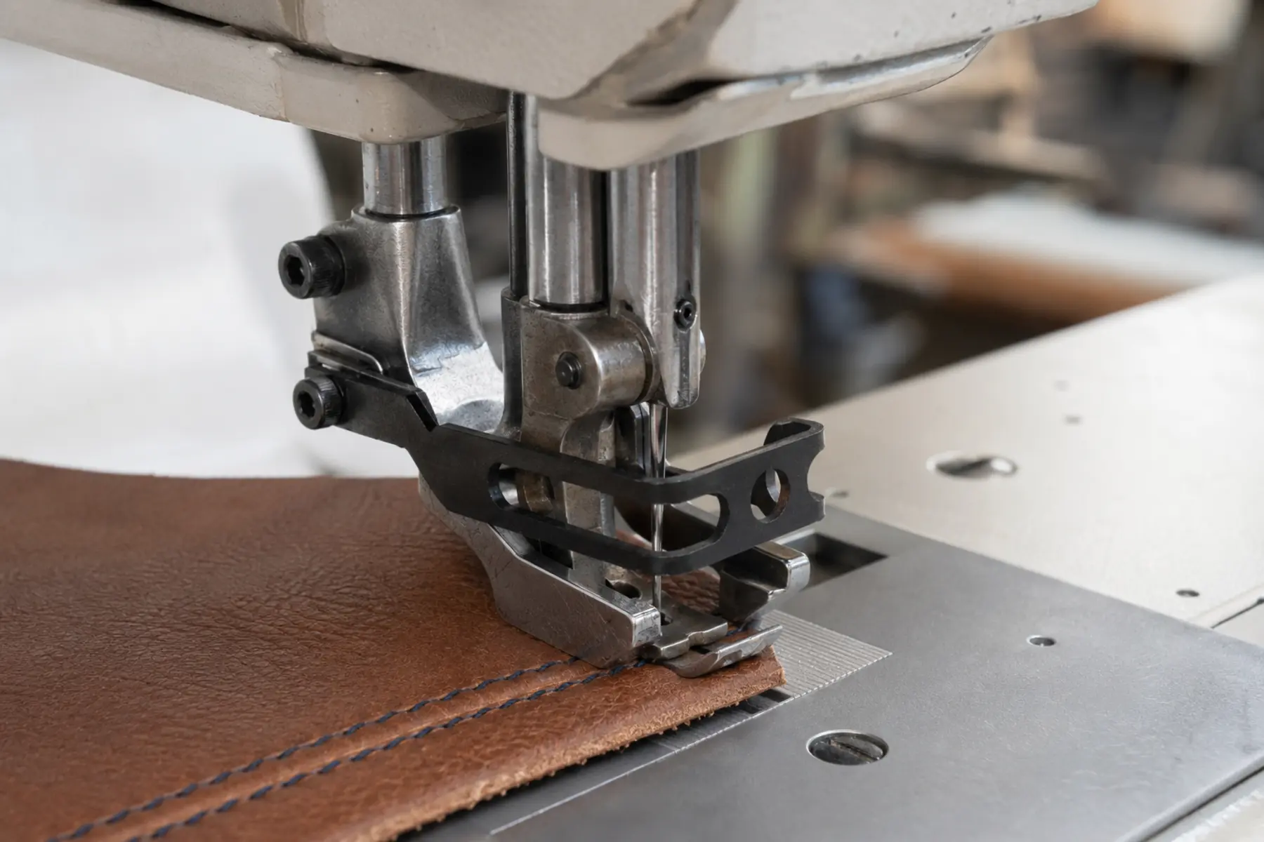 Industrial compound-feed walking foot sewing a straight seam in brown leather