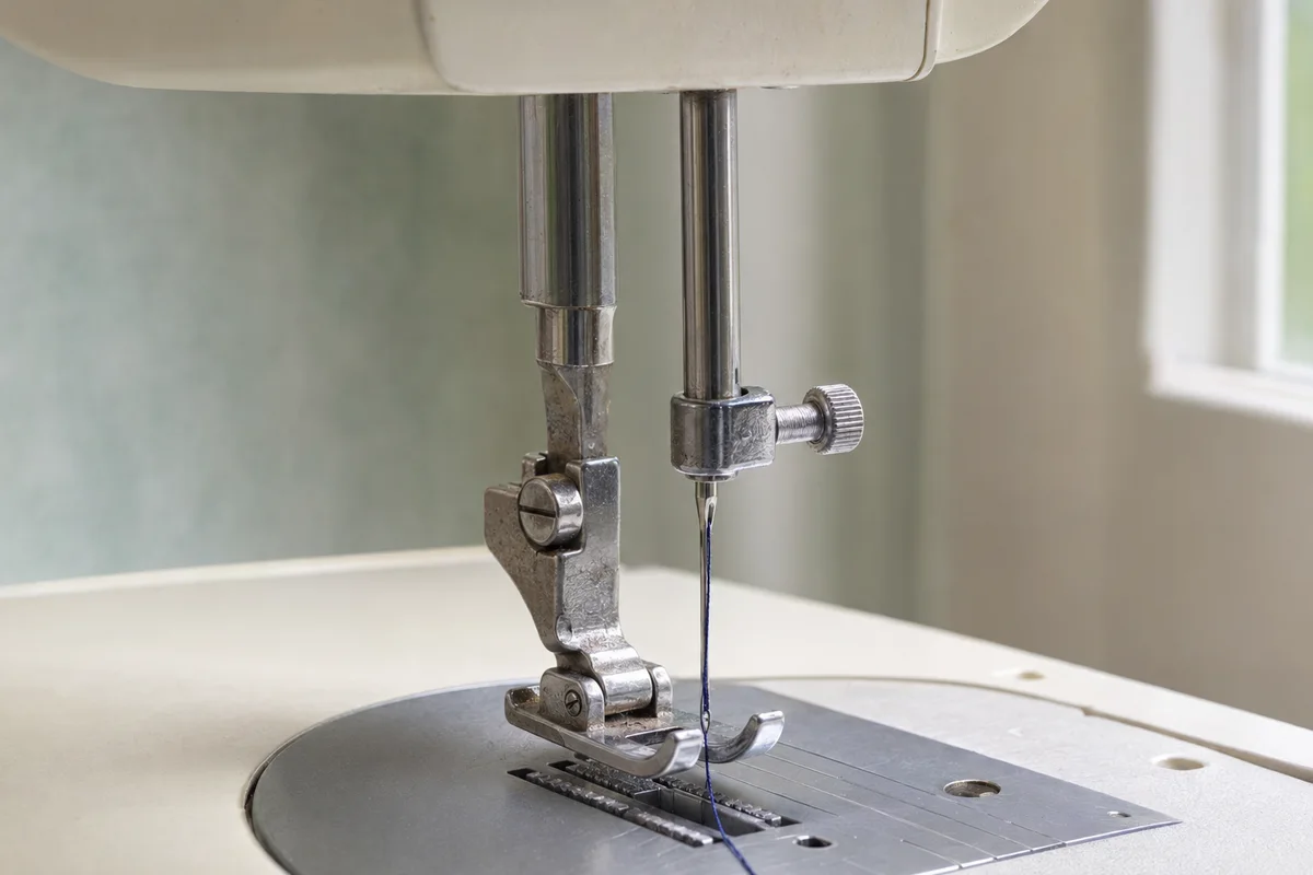 Silver domestic sewing machine needle clamp with a knurled side screw