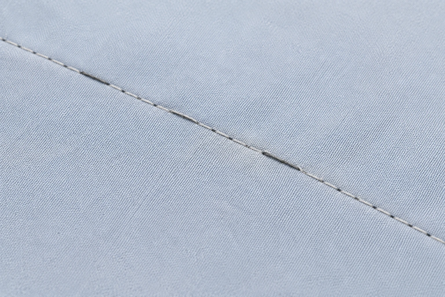 Straight seam on pale blue fabric with visible gaps where stitches failed to form