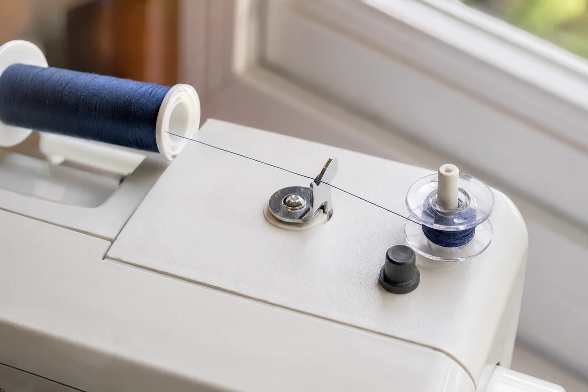 Thread spool feeding a clear bobbin on a domestic sewing machine bobbin winder