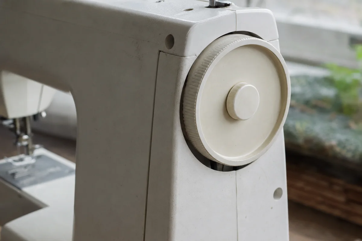 Off-white domestic sewing machine handwheel with a central clutch knob