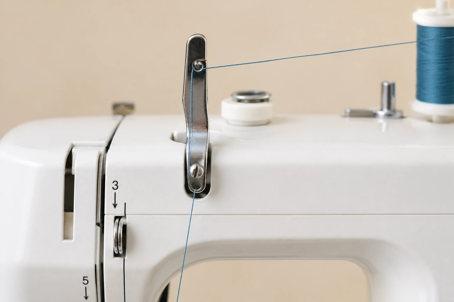 Chrome sewing machine thread take-up lever with blue thread passing through its eye