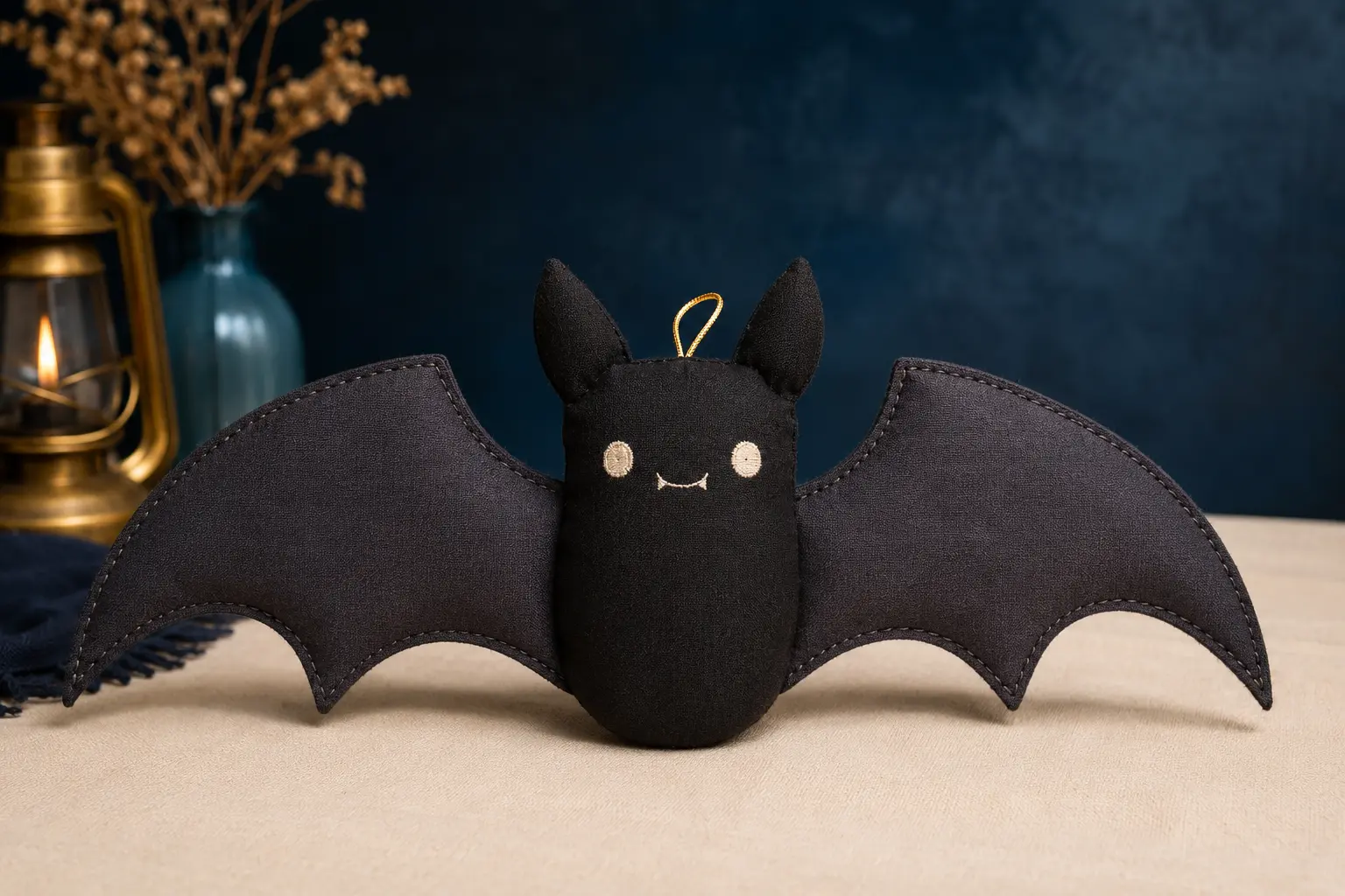 Small handmade charcoal bat plush with broad stitched wings and embroidered face